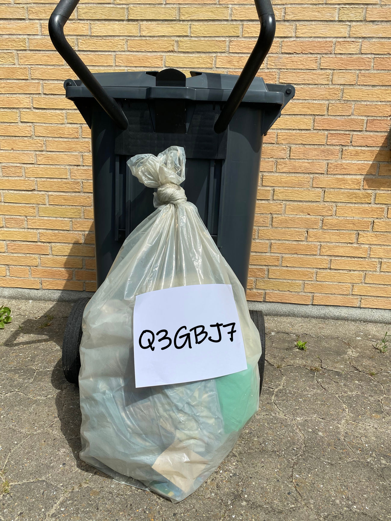 En ekstrasæk står ved kantstenen sammen med en skraldespand